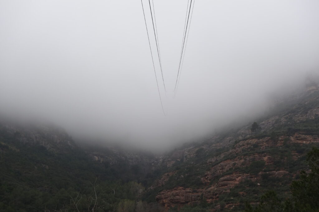Aeri de Montserrat cable car cables disappearing into the fog above the Montserrat mountains