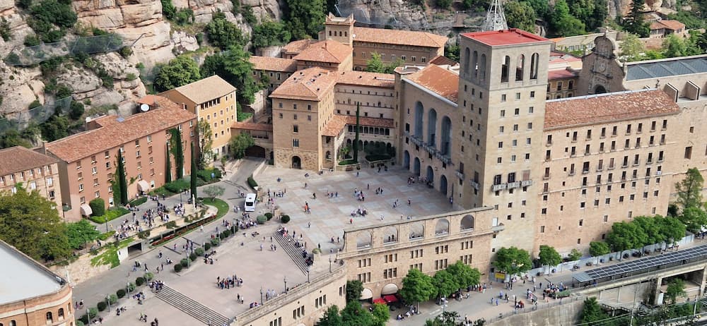 Aerial view of Montserrat Monastery and main square surrounded by mountains near Barcelona