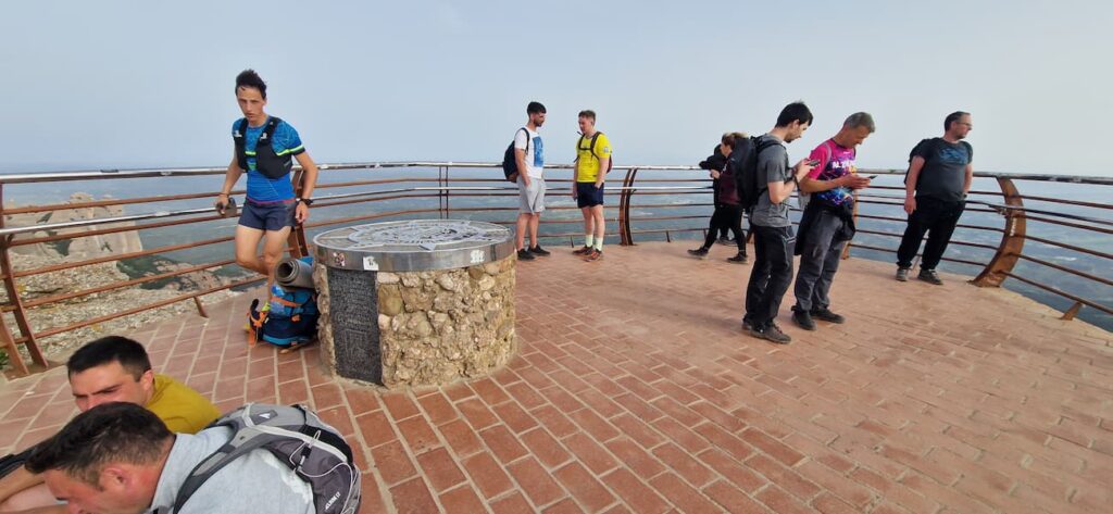 One of the most importants montserrat mountain viewpoints. Hikers enjoy the panoramic views from Sant Jeroni's summit platform at Montserrat, gathered around the orientation marker with metal railings and sweeping landscape views