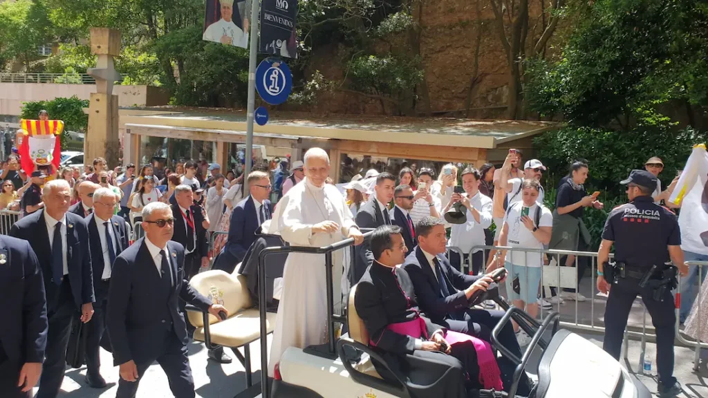 Pope Leo XIV passing welcome banners and Catalan and Peruvian flags at Montserrat
