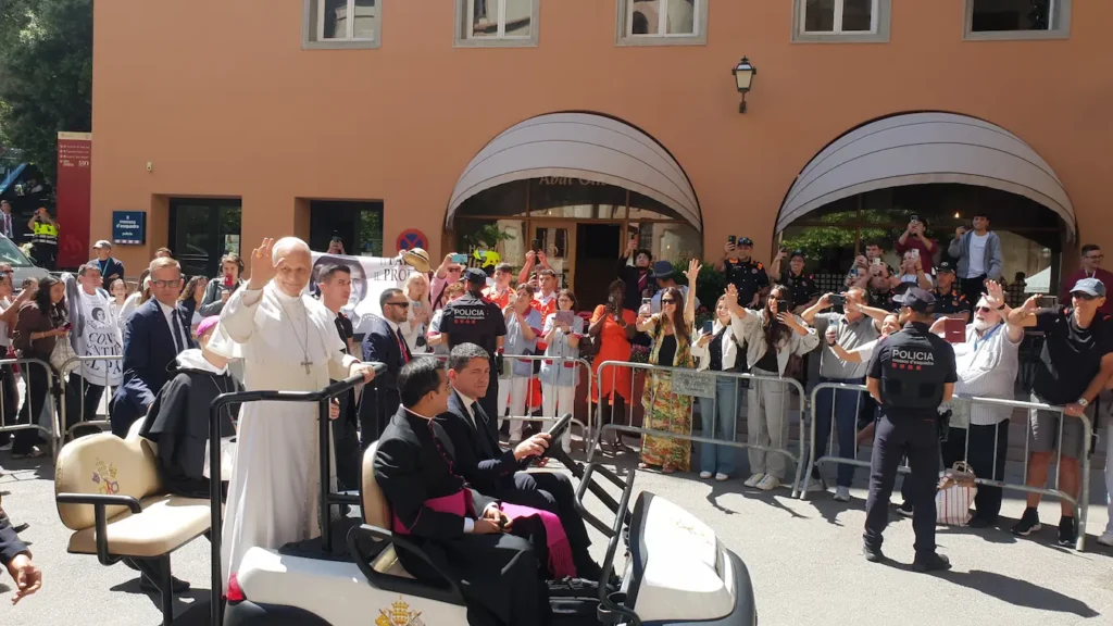 Pope Leo XIV raising his hand to pilgrims outside the Abat Cisneros building at Montserrat