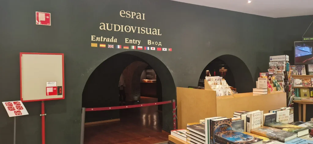Montserrat Audiovisual Space entrance arch inside the monastery bookshop, with twelve language flags above the doorway