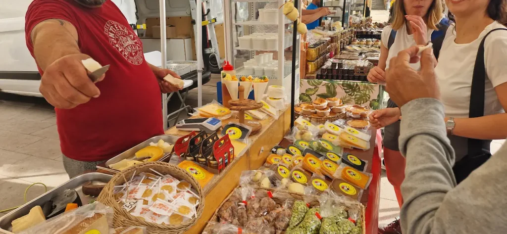 Stallholder cutting cheese for visitors to taste at the Montserrat market stalls