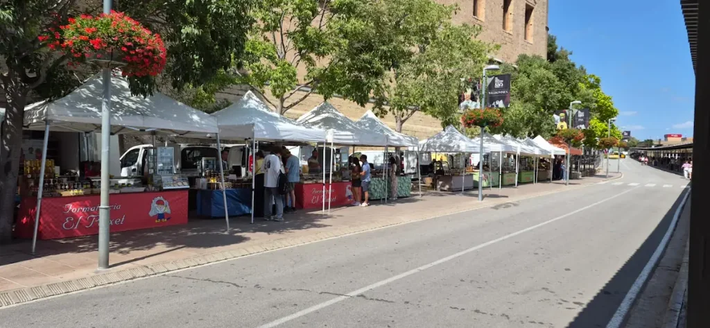 Row of white market stalls lined up under the abbey wall at Montserrat